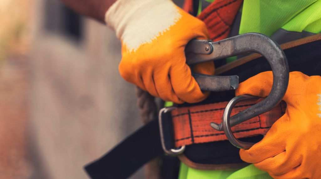 Construction worker putting on safety harness